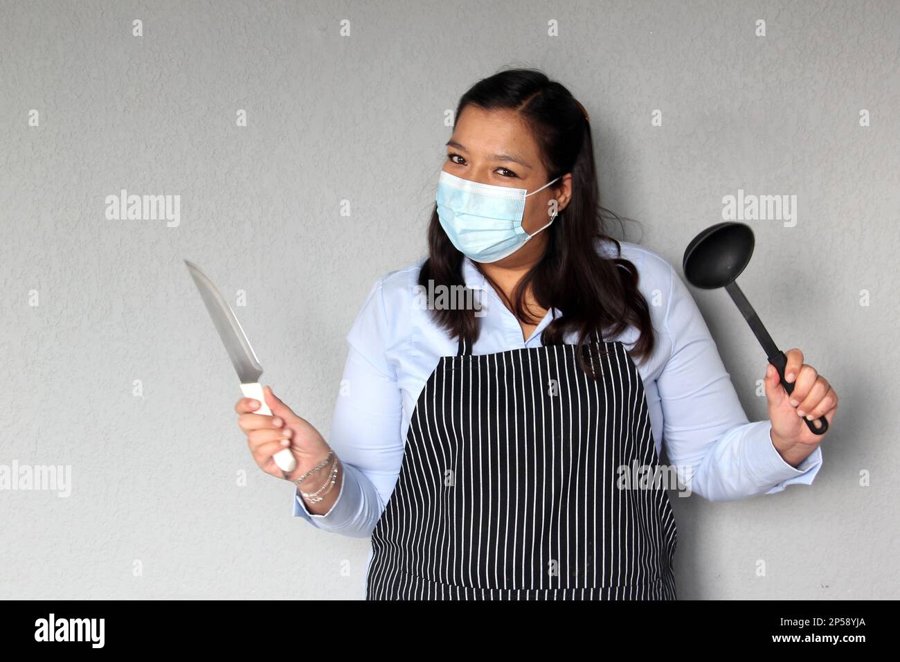 Latin chef woman with kitchen utensils working with protective mask and
