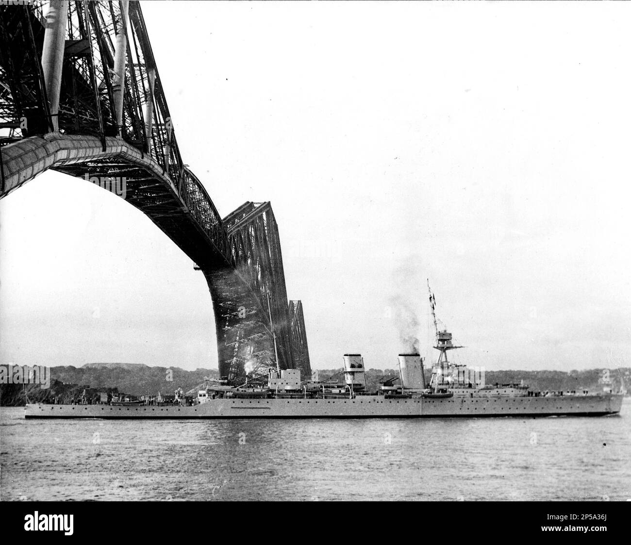 Royal Navy cruiser HMS Frobisher passes under Forth Bridge, 25 May 1937. She will be re-armed at Rosyth Dockyard and put back into operational service. Stock Photo