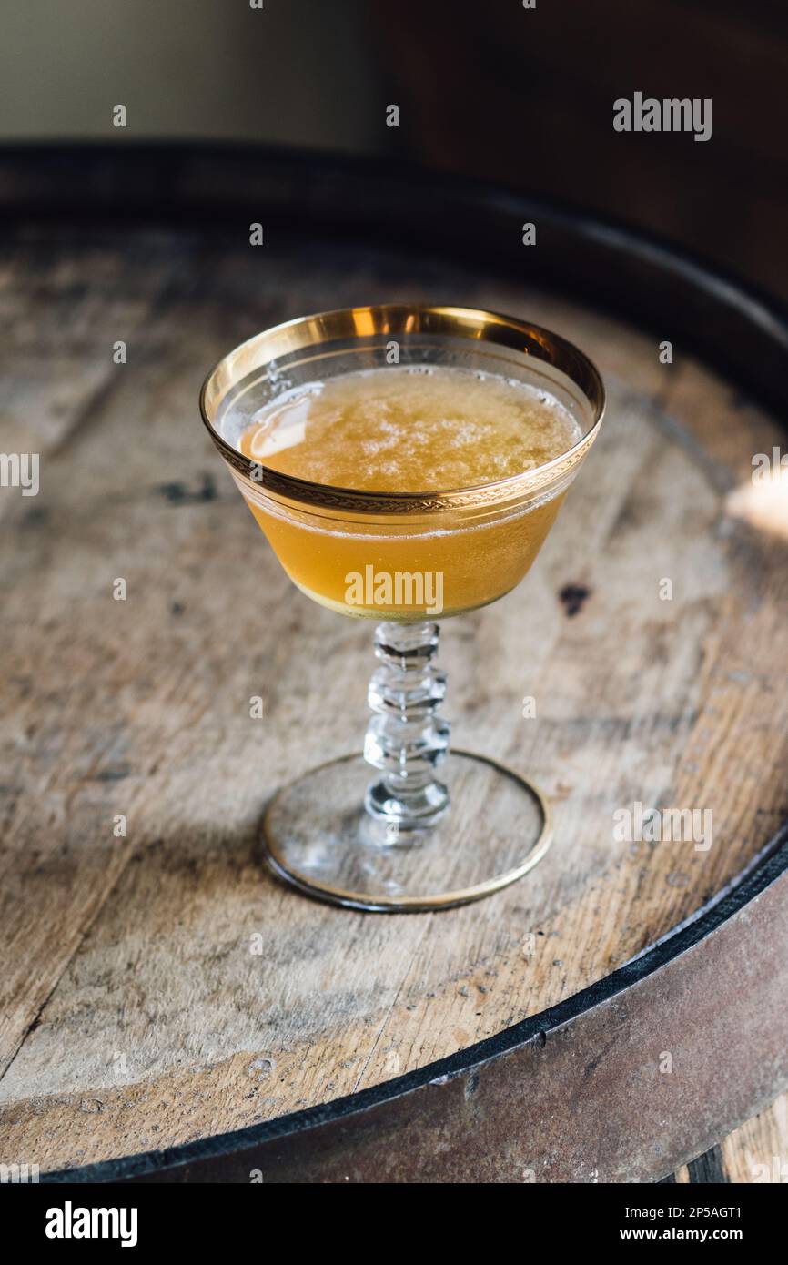 yellow whiskey cocktail in vintage hotel champagne coupe with gold rim