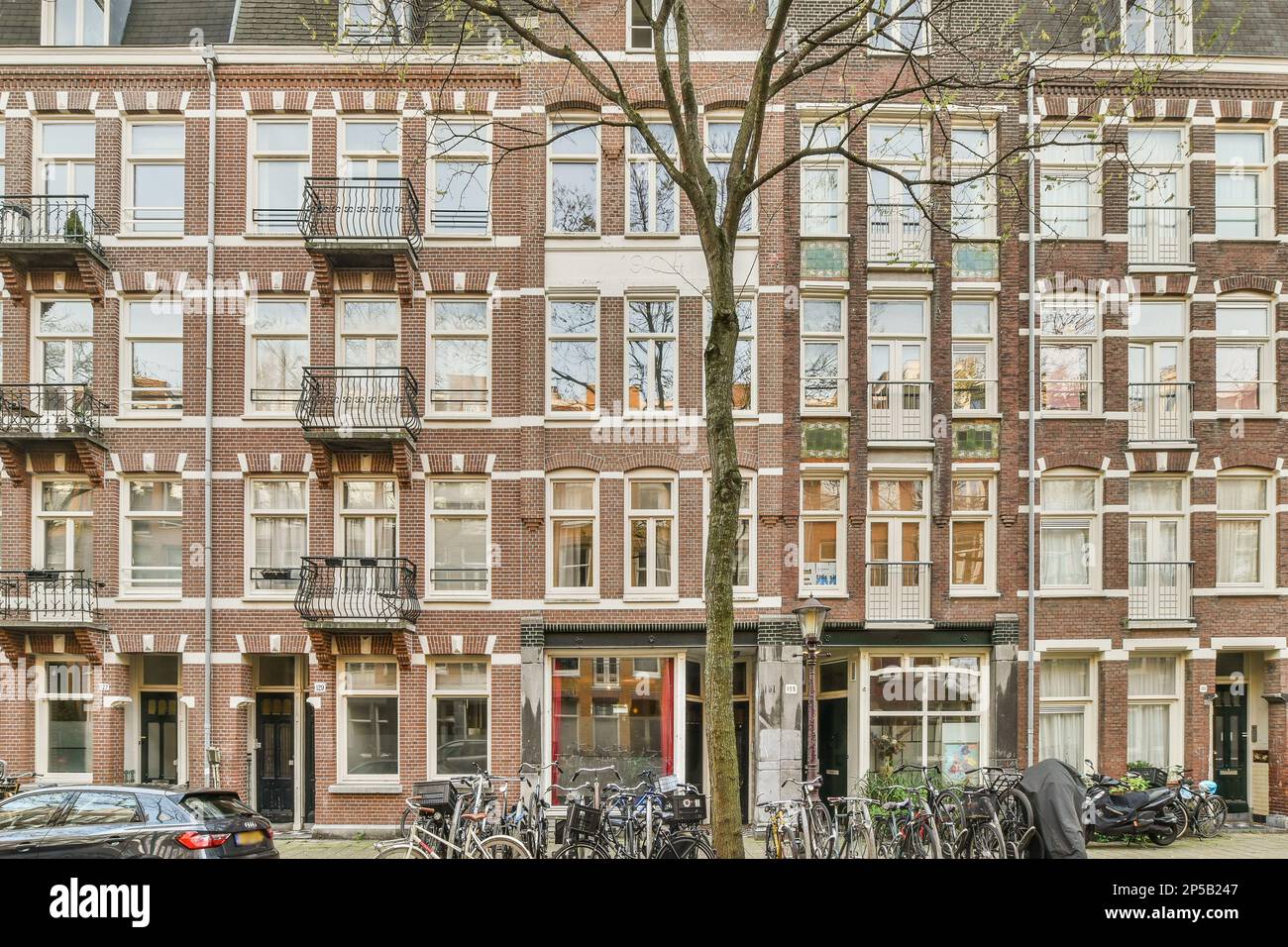 an apartment building with bicycles parked in the street and cars ...