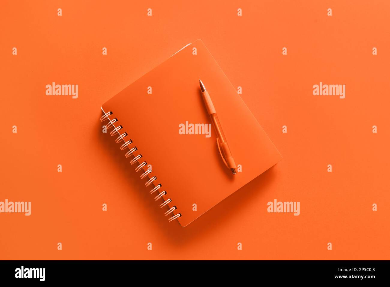 Notebook with pen on orange background Stock Photo
