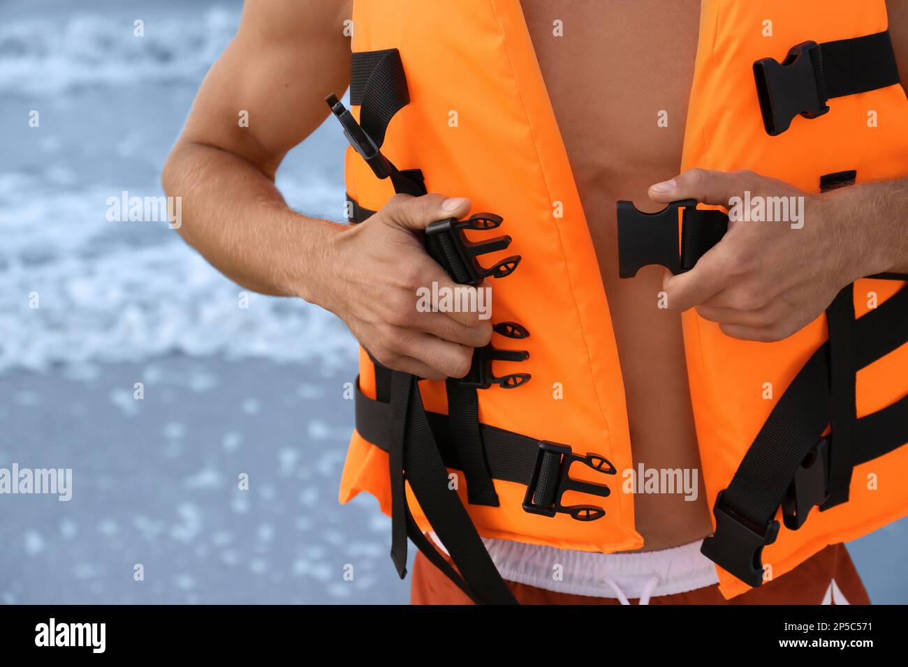 Lifeguard putting on life vest near sea, closeup Stock Photo Alamy