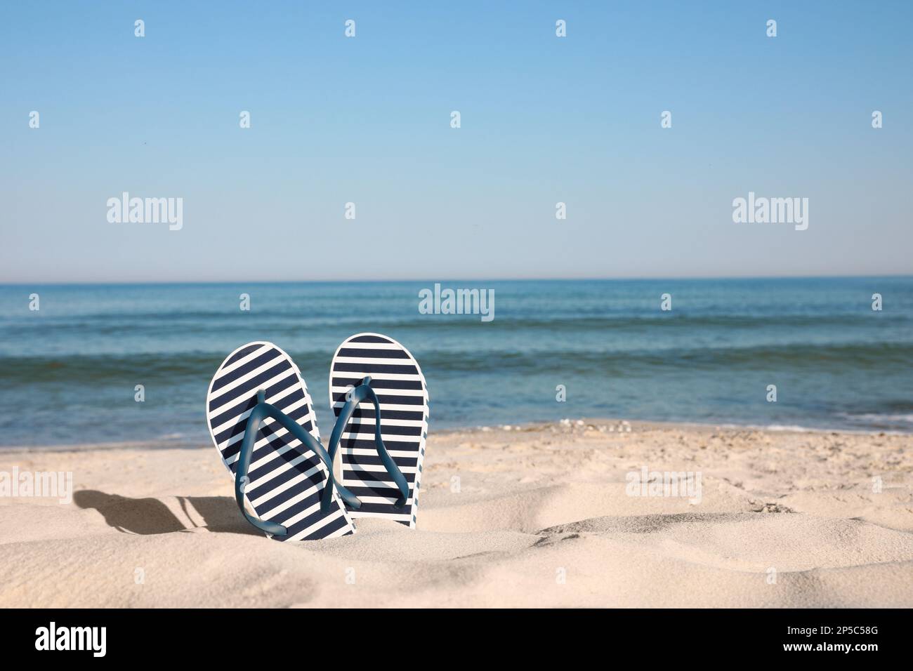 Stylish flip flops in sand on beach. Space for text Stock Photo - Alamy