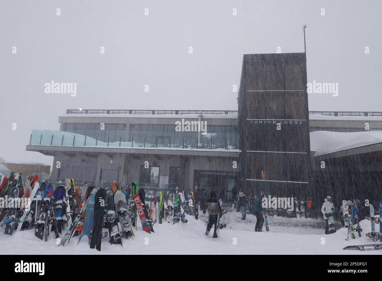 Mammoth Lakes, California. February 27, 2023. Skiers and snowboarders gather in front of Canyon Lodge during a winter blizzard at Mammoth Mountain ski Stock Photo