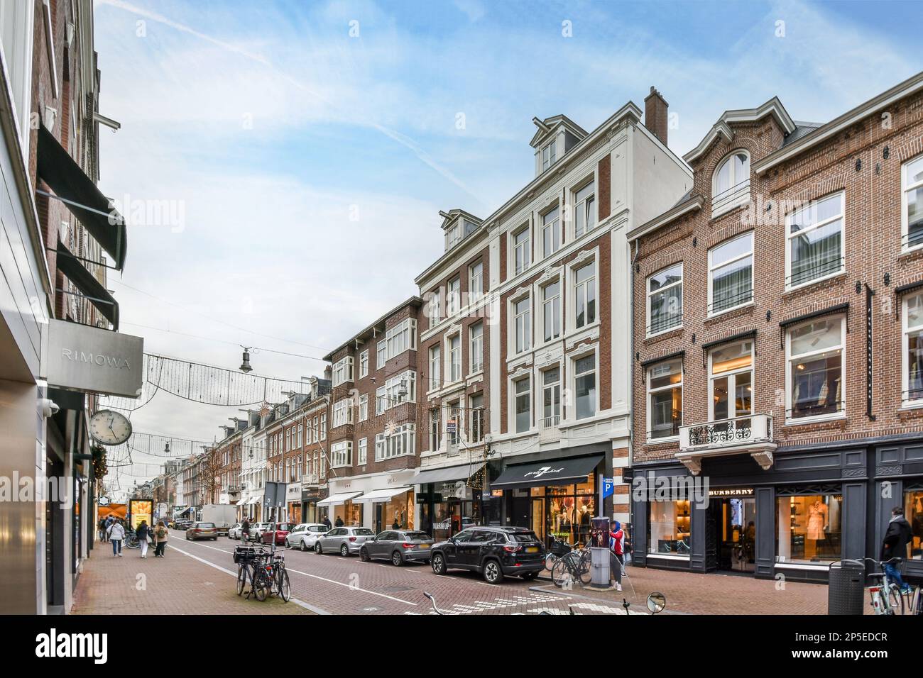 a city street with cars parked on the side and people walking down the ...