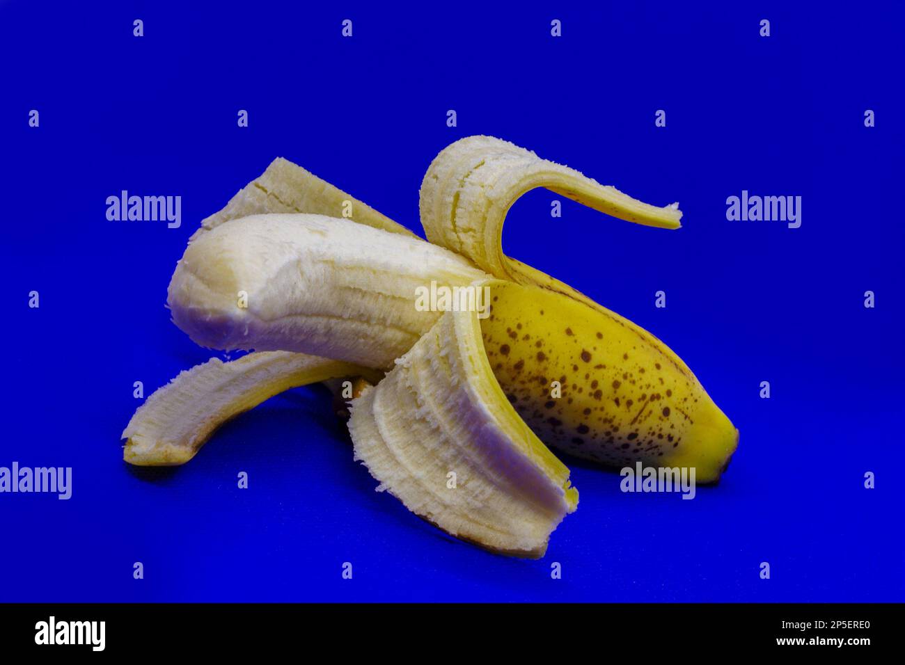 semi peeled banana placed on blue