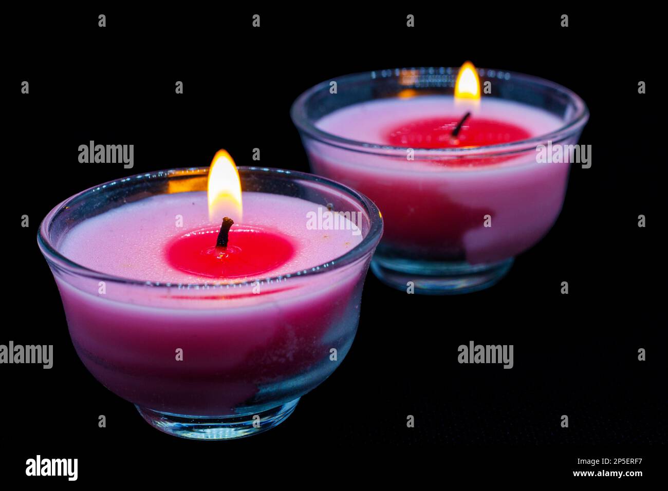 two burning candles placed on black background Stock Photo