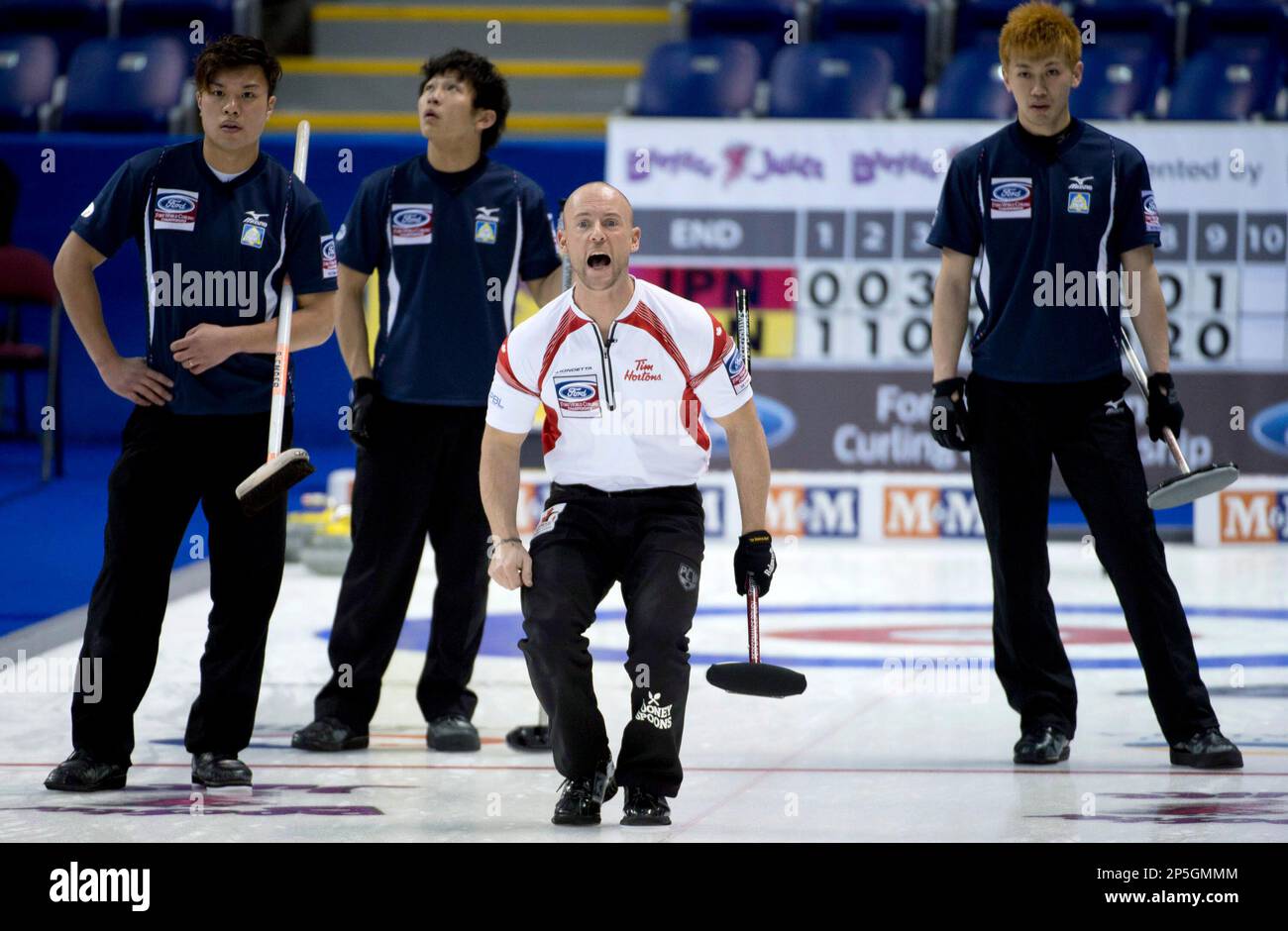 Tetsuro Shimizu, left, and Tsuyoshi Yamaguchi of Japan sweep against Switzerland in their eighth session of the round robin during the World Mens Curl Stock Photo