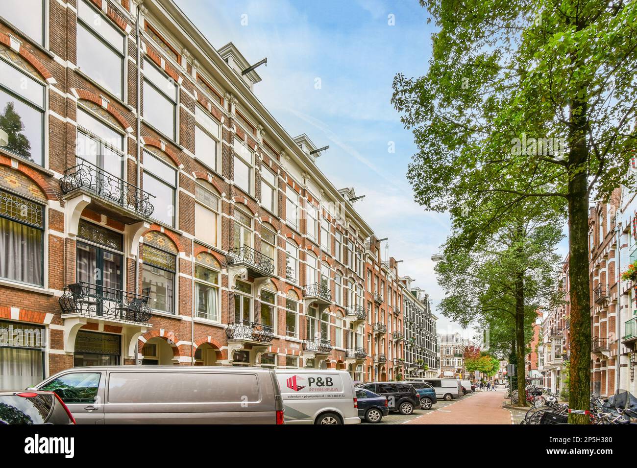 a city street with cars parked on the side and trees lining the ...