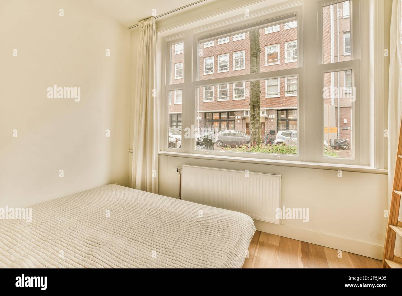 a bedroom with a bed, ladders and window in the fore - image was taken from an actual photograph Stock Photo