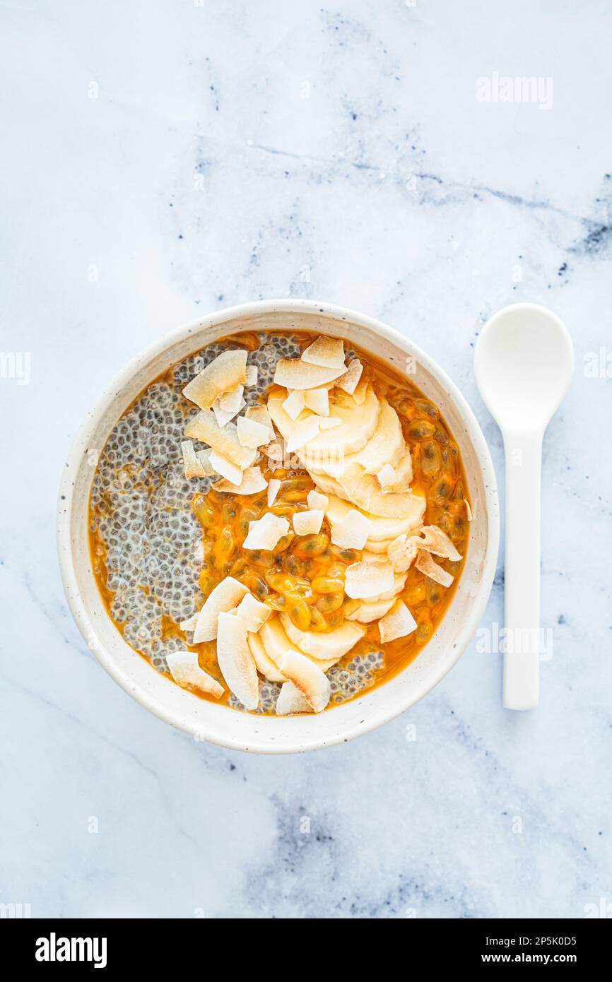 Chia pudding with passion fruit, coconut and coconut yogurt in white bowl, top view. Healthy vegan recipe. Stock Photo