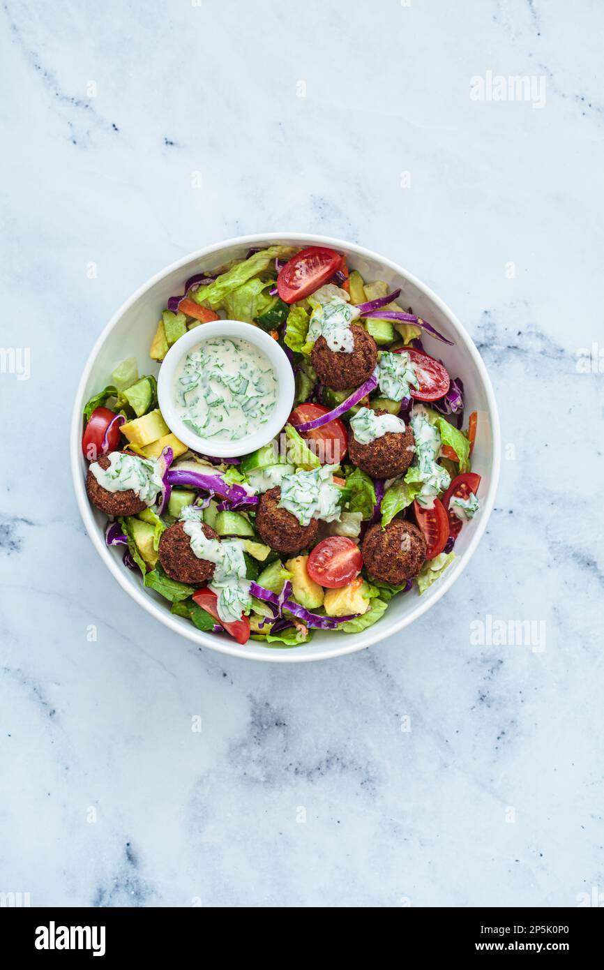 Falafel salad with avocado, tomato and tahini dressing, top view