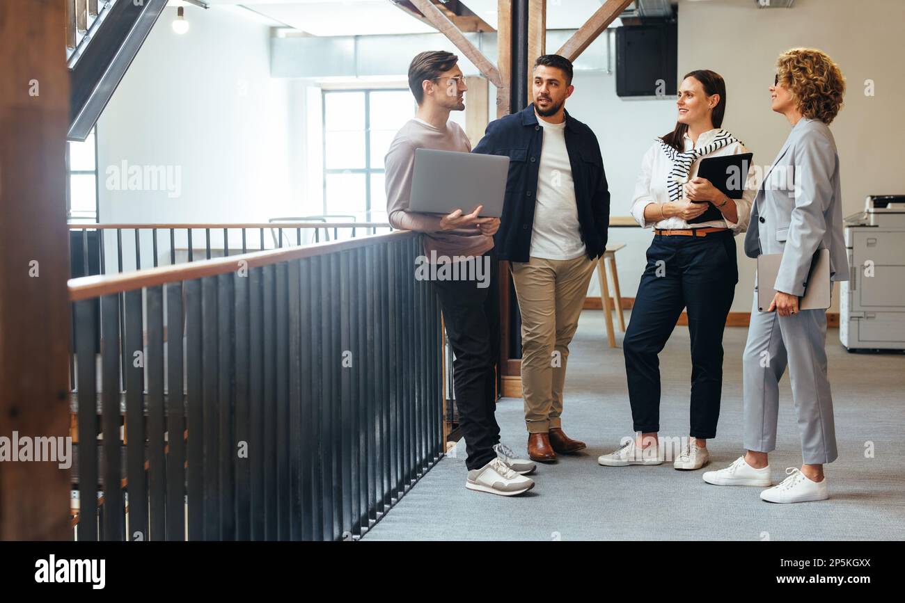 Tech professionals having a standup meeting in an office. Business people stand together and discuss their work progress in an office. Creative busine Stock Photo
