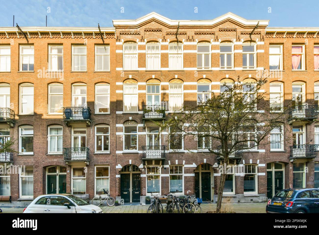 an apartment building with cars parked on the street next to it and two ...