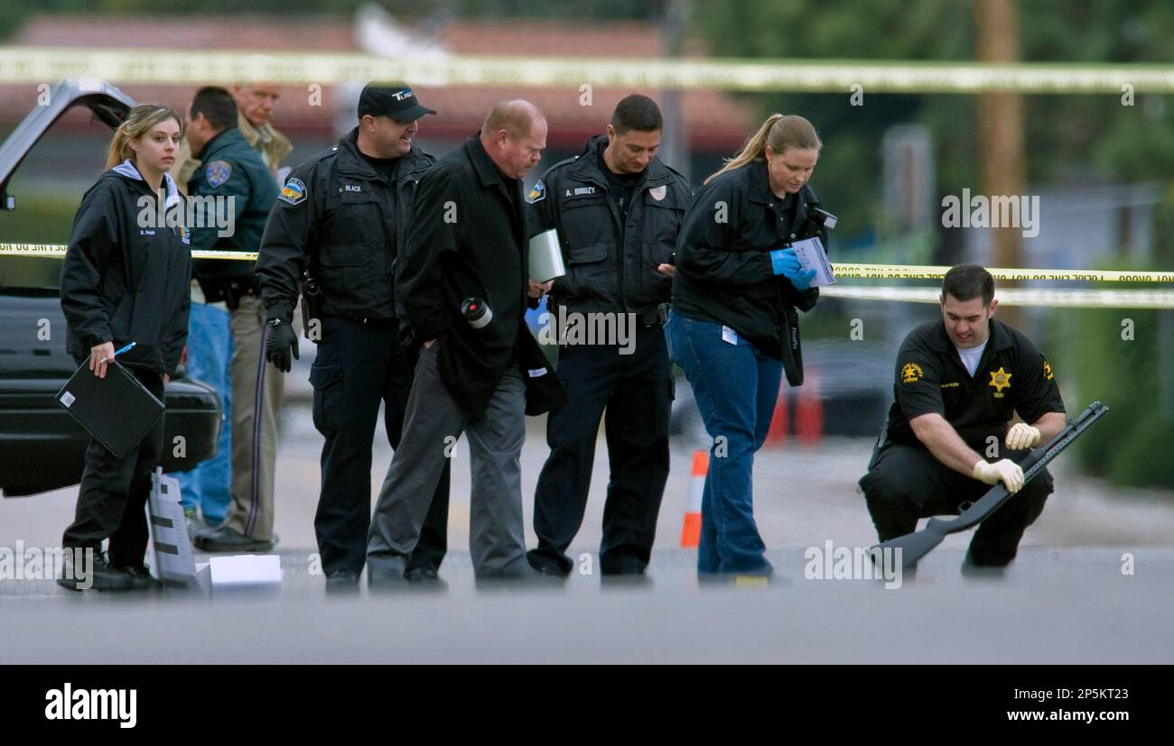 Police investigators examine a gun laying in the street at the intersection of Wanda Road and