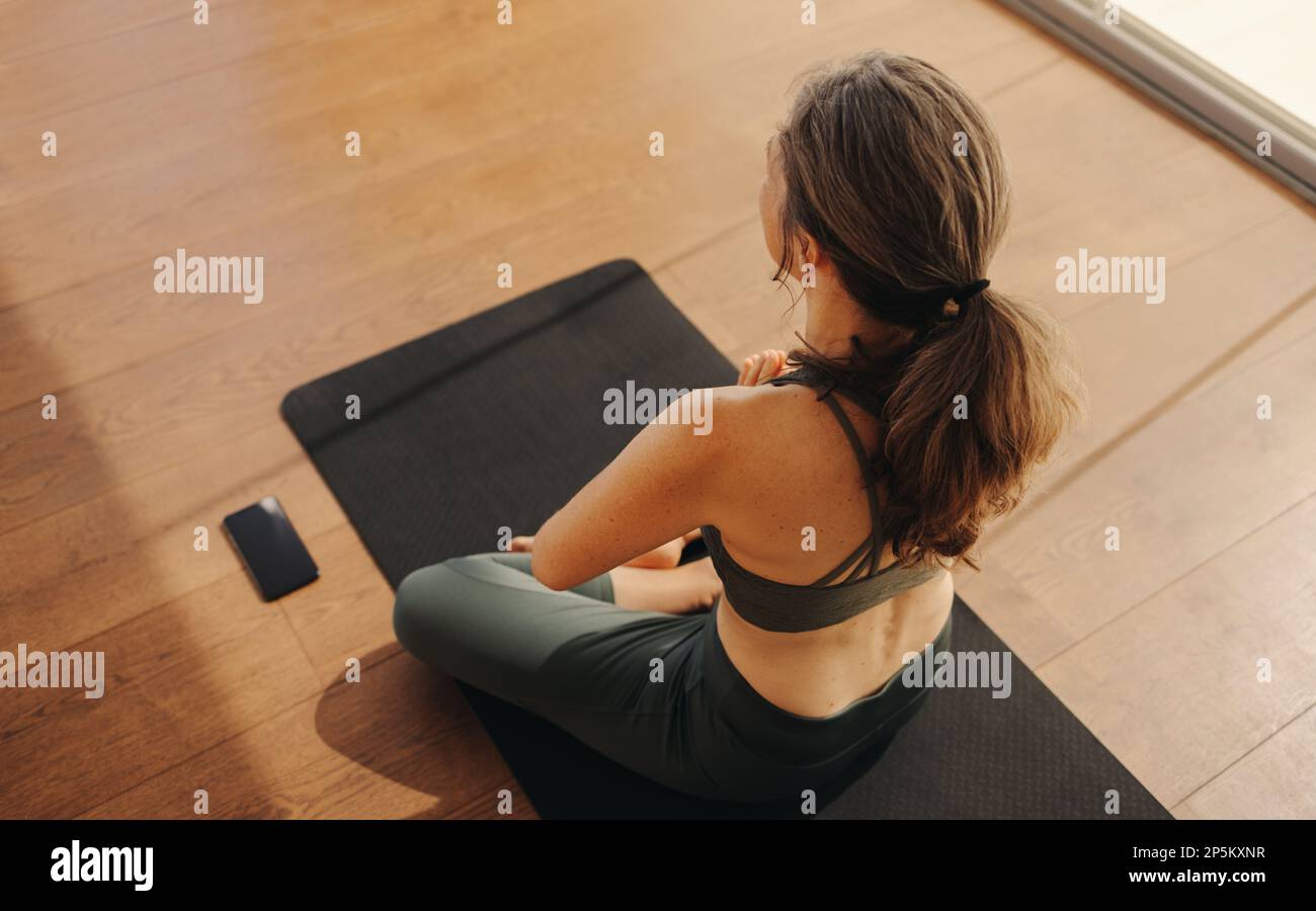 High angle view of a mature woman meditating in prayer position. Woman doing a relaxation exercise during a yoga session. Senior woman practicing a he Stock Photo