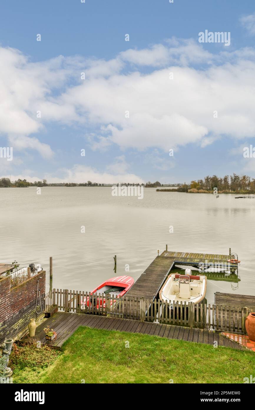 a boat docked on the water's edge with a cloudy blue sky in the ...