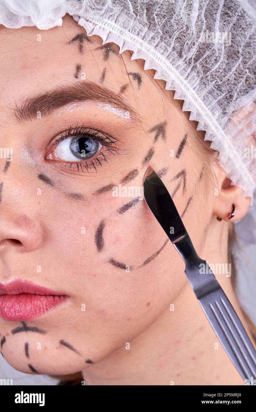 Closeup of scalpel near young womans face. Beauty Operation concept