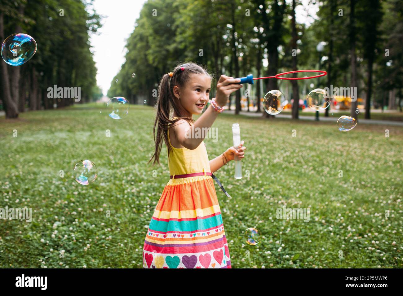 Impressed little girl blows bubbles in the park Stock Photo - Alamy