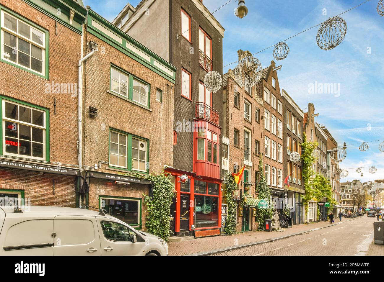 a city street with cars parked on the side and people walking down the ...