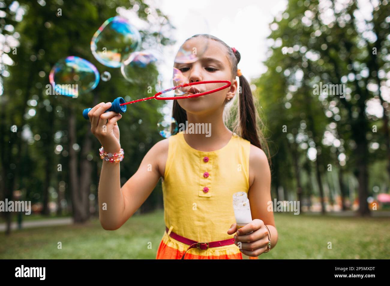 Rapt little girl blows bubbles in the park Stock Photo - Alamy