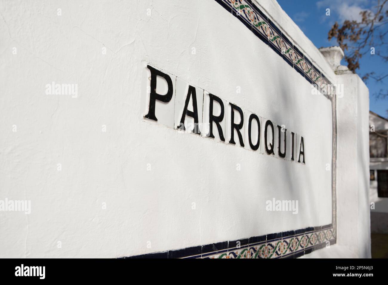 Parish sign in spanish with glazed tiles over whitewashed wall. Selective focus Stock Photo Alamy
