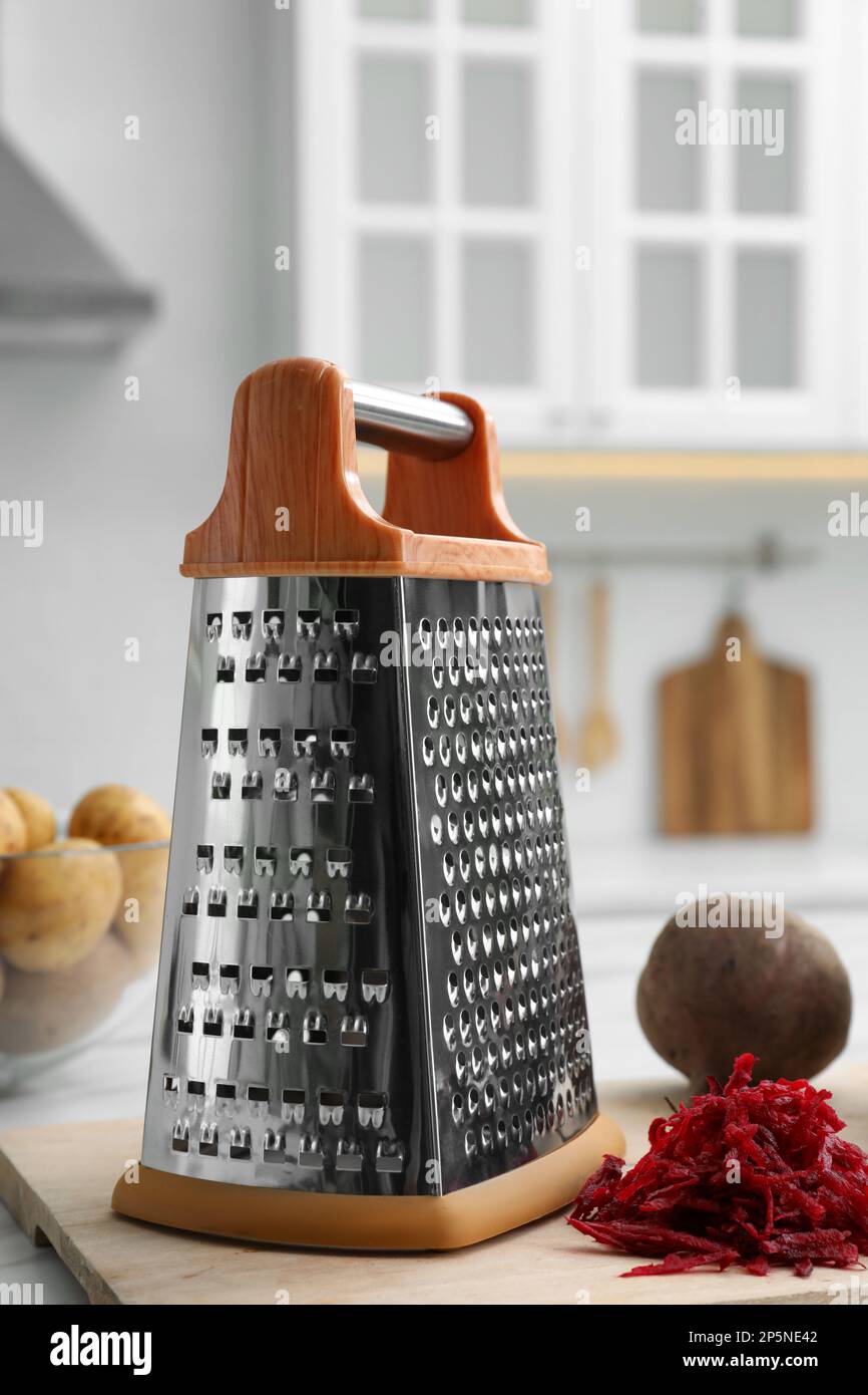 Grater and fresh ripe beetroot on table in kitchen Stock Photo