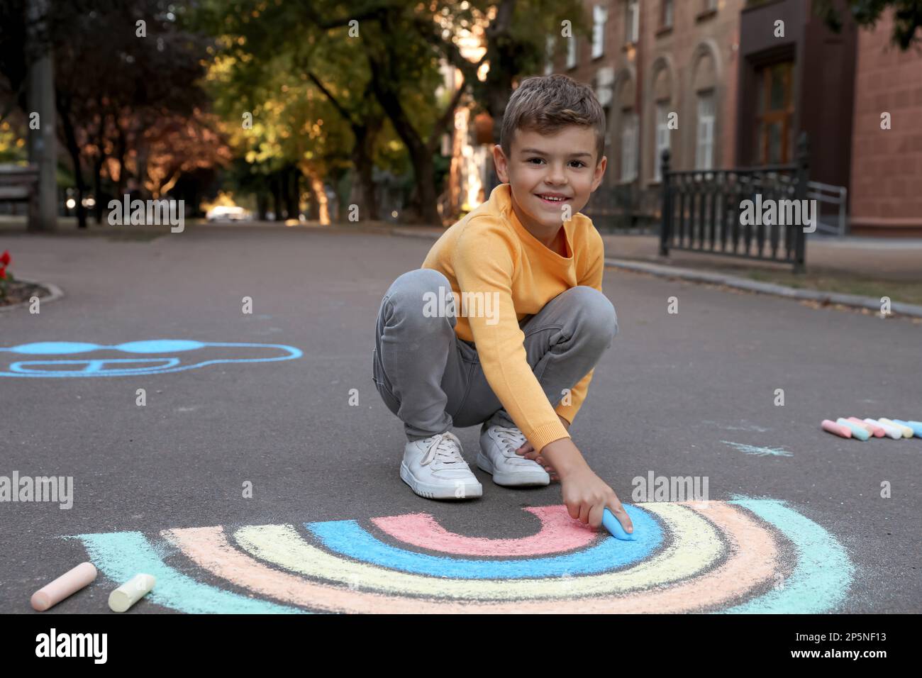 Happy child drawing rainbow with chalk on asphalt Stock Photo - Alamy