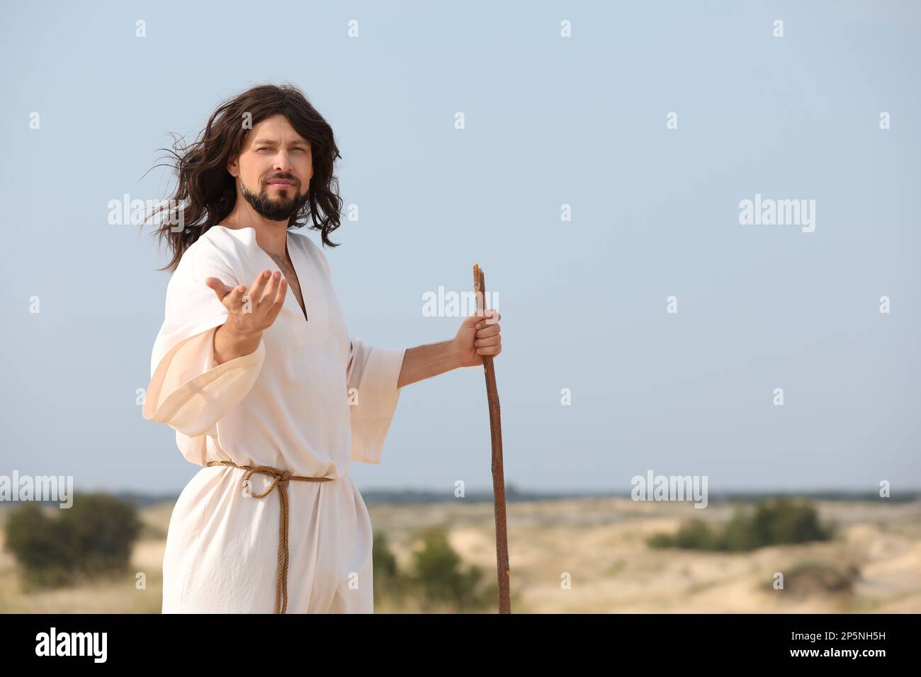 Jesus Christ walking with stick in desert. Space for text Stock Photo