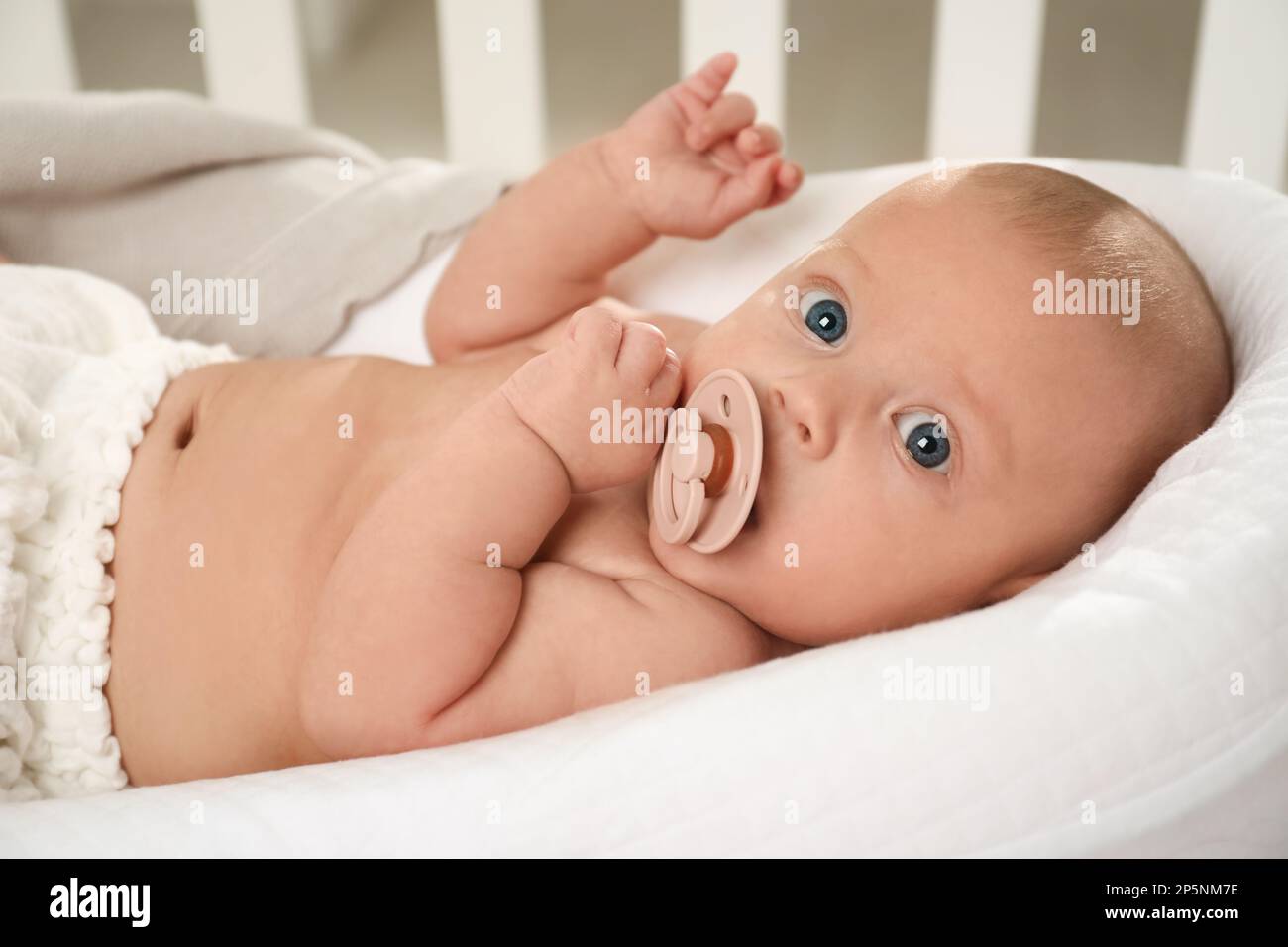 Cute little baby with pacifier lying in crib Stock Photo Alamy