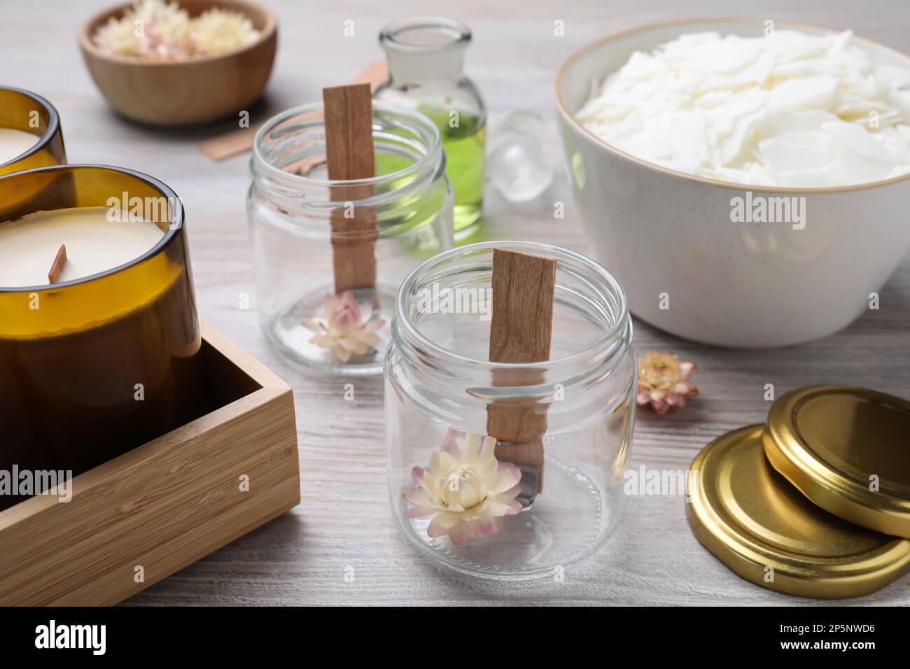 Glass jars with wicks and flowers on light wooden table. Making ...