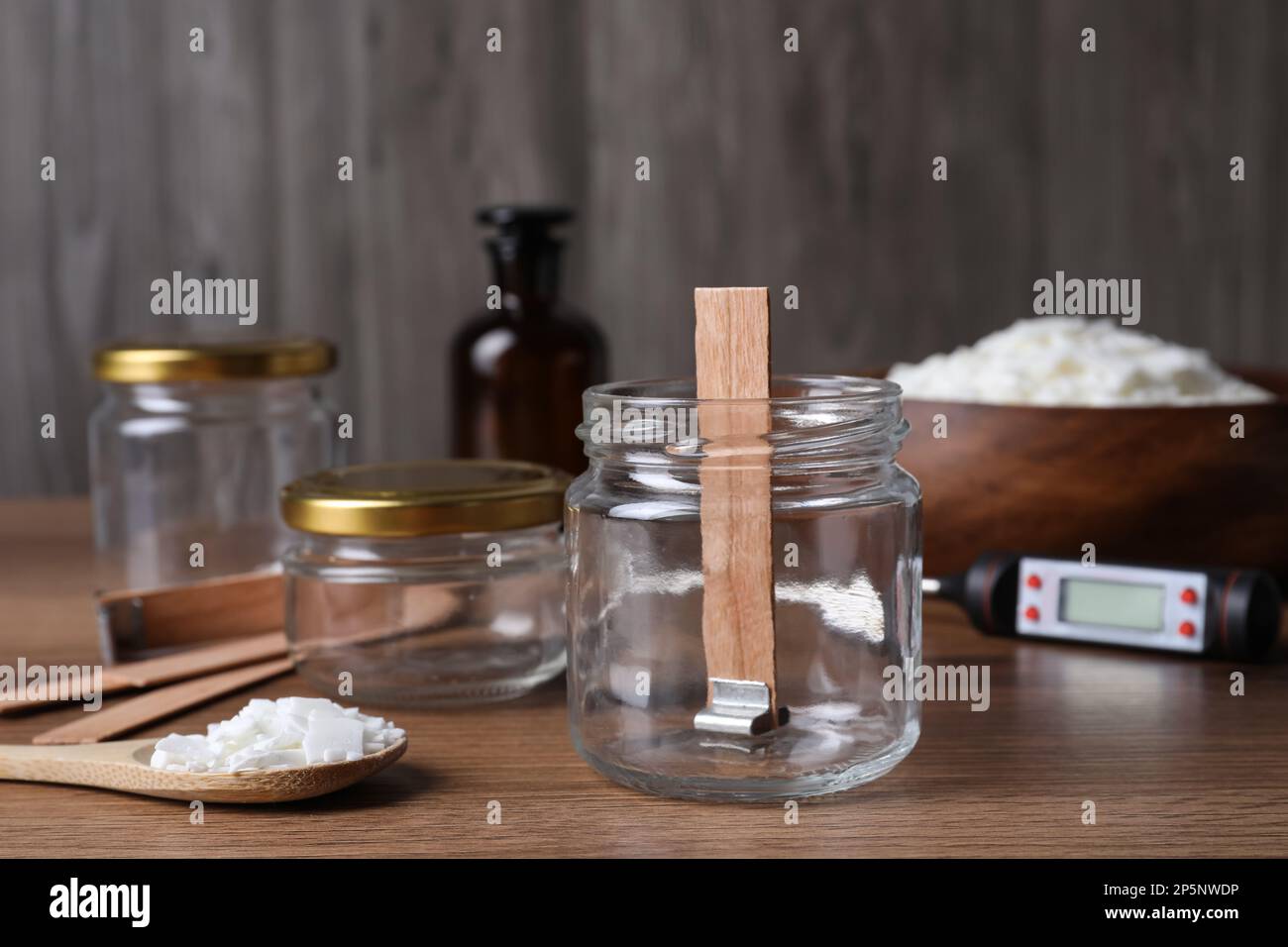 Glass jar with wick and wax flakes on wooden table. Making homemade ...