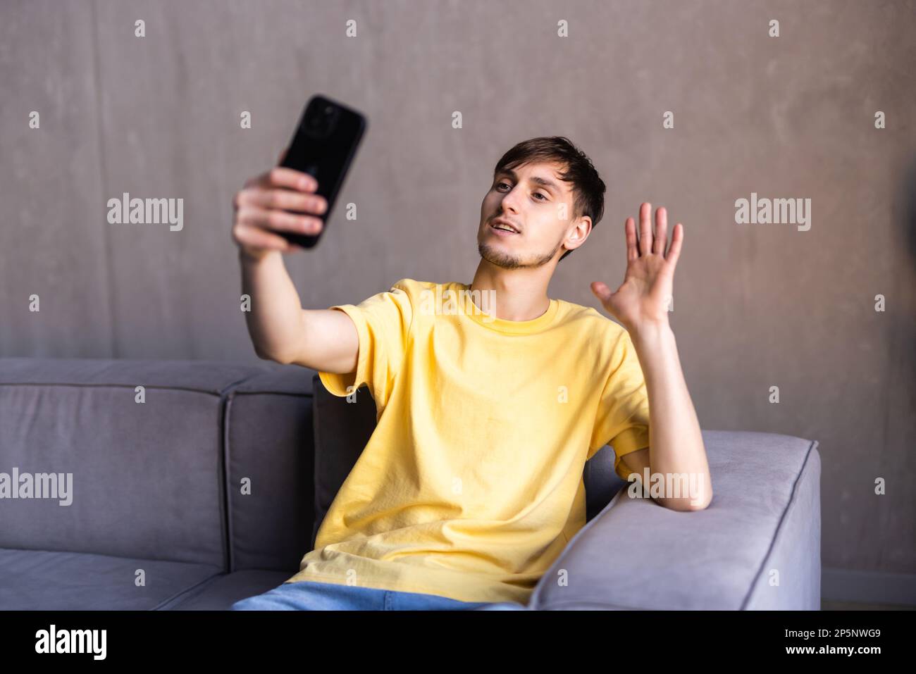 Positive engaged young business man using wireless earbud and mobile