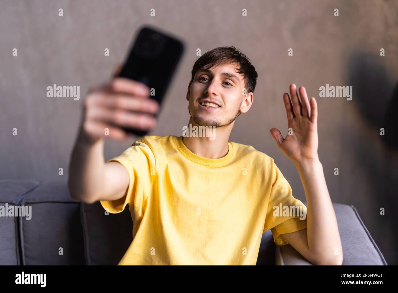 Positive engaged young business man using wireless earbud and mobile