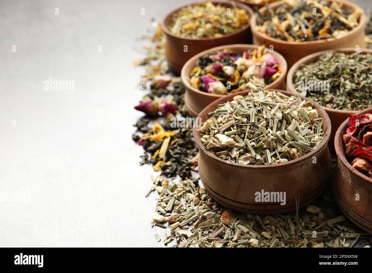 Flat lay composition with different dry teas on light grey table, space ...