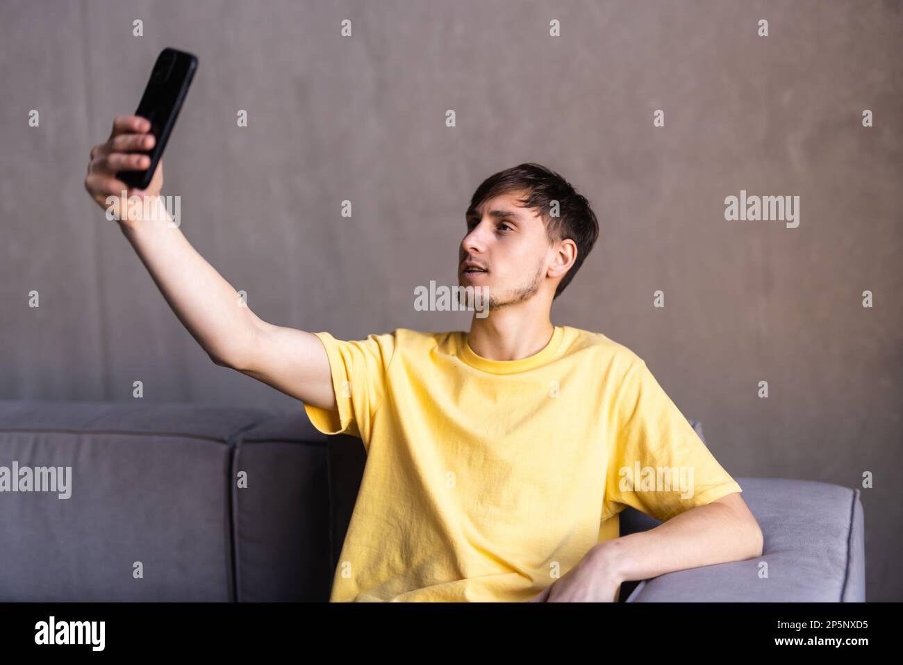 Positive engaged young business man using wireless earbud and mobile ...