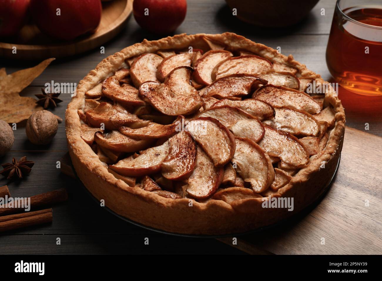 Delicious apple pie, ingredients and cup of tea on wooden table Stock Photo