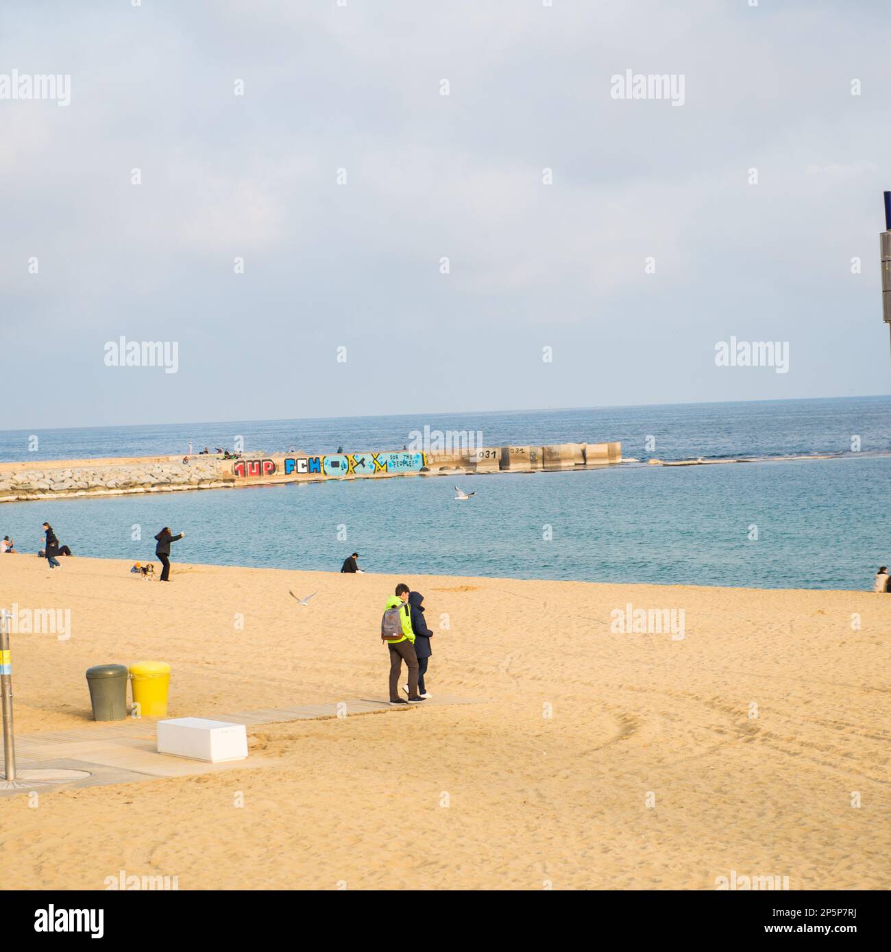 Barcelona,Spain-February 22,2023:Families stroll in the beach late in the afternoon Stock Photo