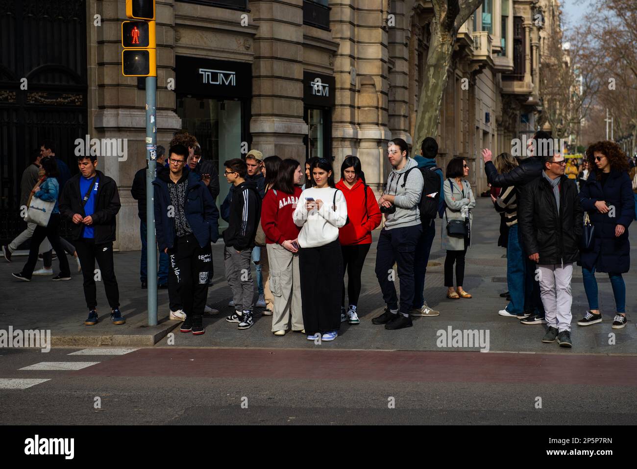 Barcelona,Spain-February 22,2023:Pedestrians wait at a busy street crossing while talking among themselves. Stock Photo