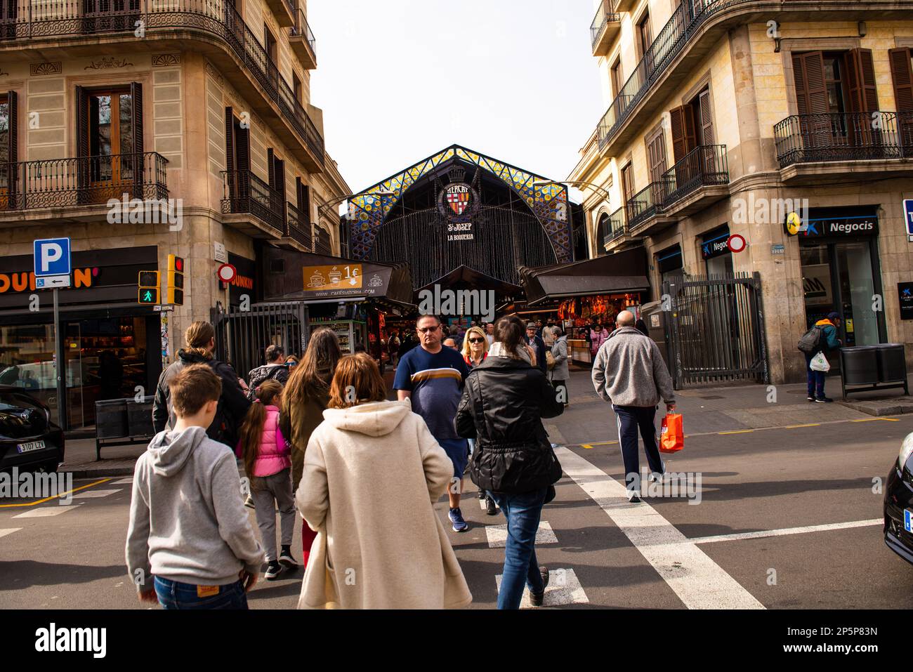 Barcelona,Spain-February 22,2023:People cross the street in front of the entrance to la Boqueria market Stock Photo