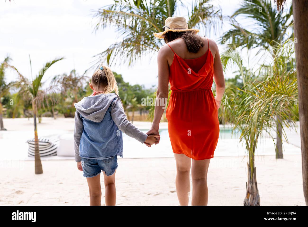 Happy biracial mother and daughter holding hands at beach Stock Photo
