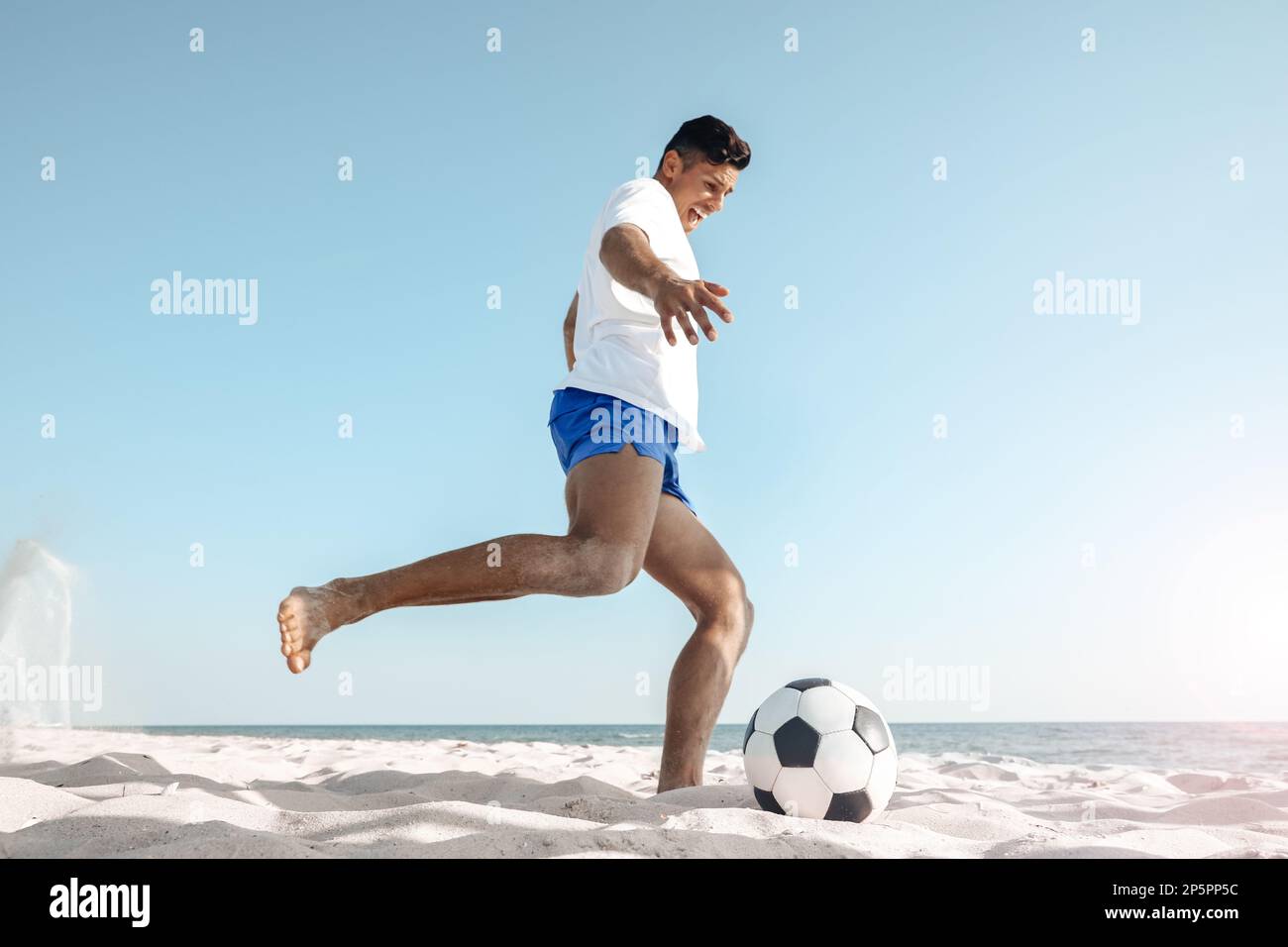 Man kicking football ball on beach near sea Stock Photo Alamy