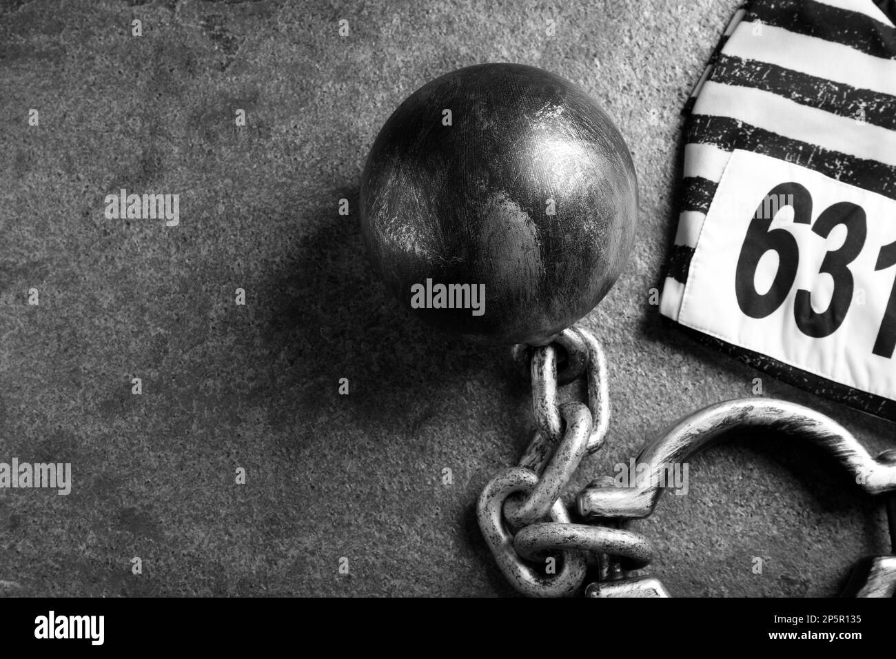 Prisoner ball with chain and jail clothes on grey table, flat lay