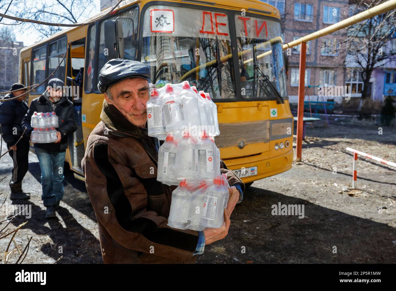 Men carry bottles with hand sanitizer towards a library, as local residents come there to get warm, charge their electric devices, read books and daily newspapers in the course of Russia-Ukraine conflict in the town of Zolote (Zolotoye) in the Luhansk region, Russian-controlled Ukraine, March 6, 2023. REUTERS/Alexander Ermochenko Stock Photo