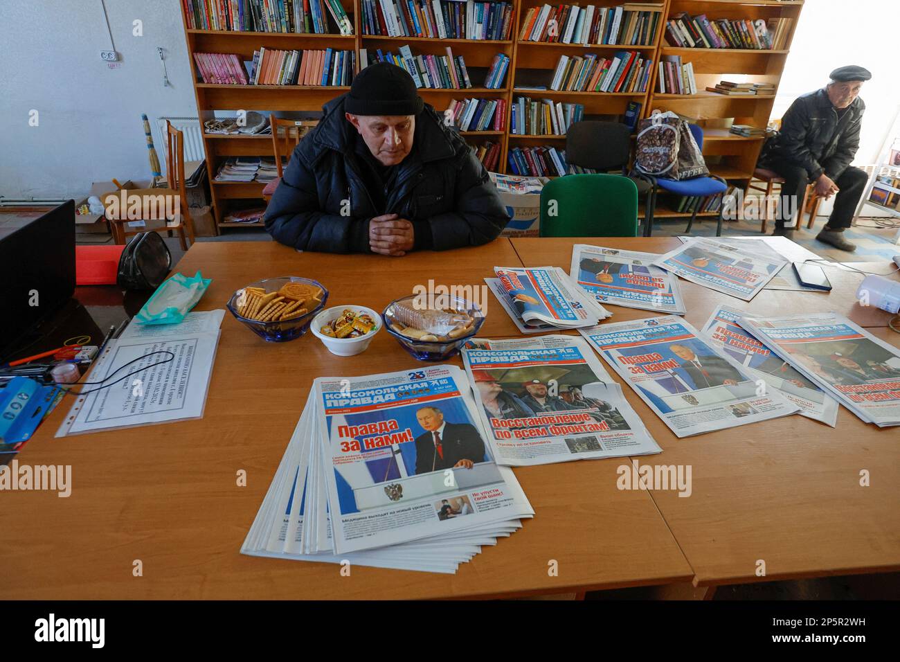 Local residents come to a library to get warm, charge their electric devices, read books and daily newspapers in the course of Russia-Ukraine conflict in the town of Zolote (Zolotoye) in the Luhansk region, Russian-controlled Ukraine, March 6, 2023. A front page of a newspaper shows an image of Russian President Vladimir Putin and a headline reads: 'The truth is ours!' REUTERS/Alexander Ermochenko Stock Photo