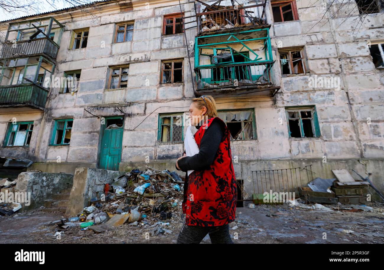 Head of a settlement council Svetlana Magur, 59, walks past a destroyed building while visiting local residents in the course of Russia-Ukraine conflict in the town of Zolote (Zolotoye) in the Luhansk region, Russian-controlled Ukraine, March 6, 2023. REUTERS/Alexander Ermochenko Stock Photo