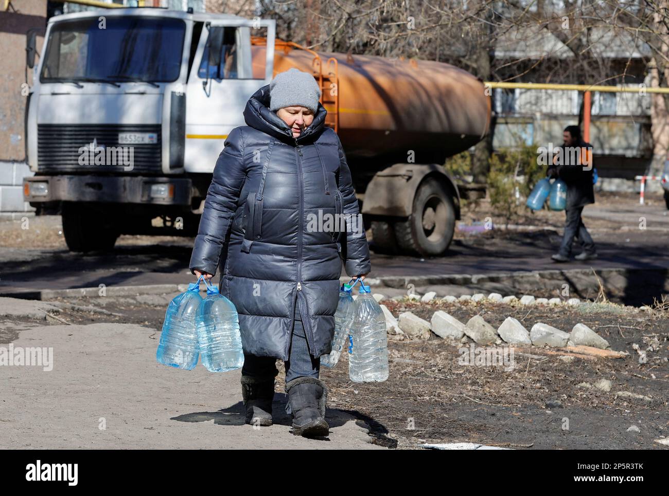 A local resident carries bottles with water in the course of Russia-Ukraine conflict in the town of Zolote (Zolotoye) in the Luhansk region, Russian-controlled Ukraine, March 6, 2023. REUTERS/Alexander Ermochenko Stock Photo