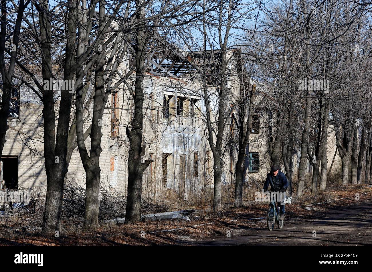 A local resident rides a bicycle past a destroyed building in the course of Russia-Ukraine conflict in the town of Zolote (Zolotoye) in the Luhansk region, Russian-controlled Ukraine, March 6, 2023. REUTERS/Alexander Ermochenko     TPX IMAGES OF THE DAY Stock Photo