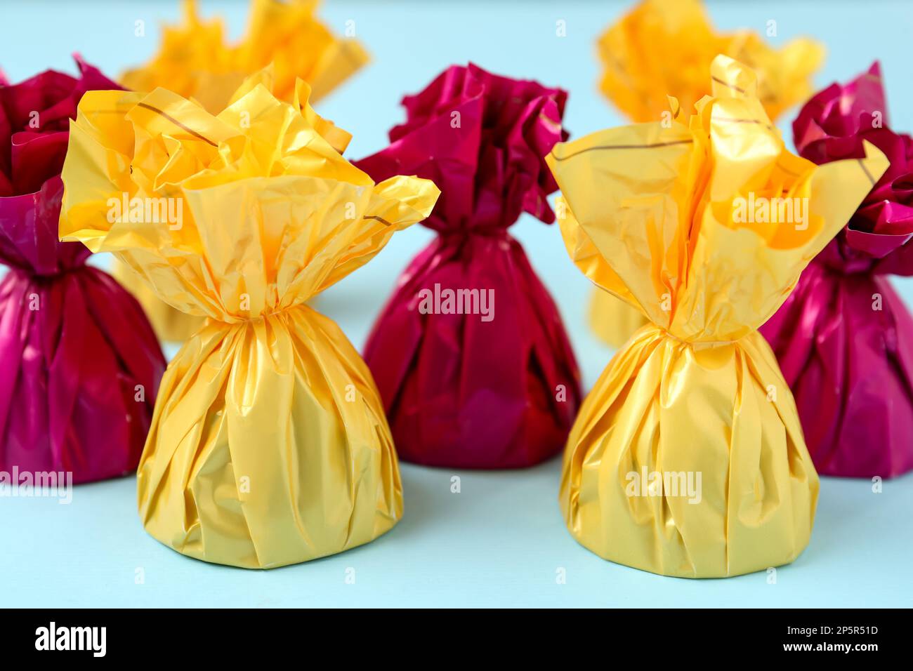 Candies in colorful wrappers on light blue background, closeup Stock