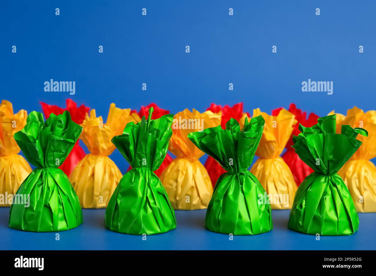 Candies in colorful wrappers on blue background Stock Photo - Alamy
